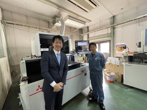 山田製作所の工場で並ぶ担当の船着と代表取締役 栗尾健司様