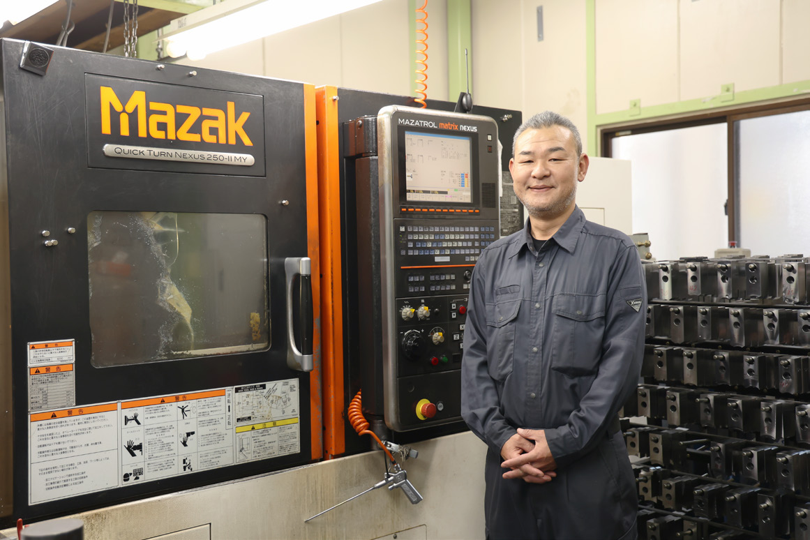 岩井製作所の工場内で複合加工機の前に立つ担当者